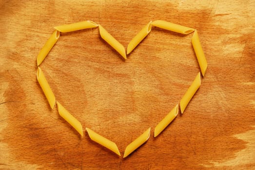 Italian farfalle pasta forming a heart on wood background