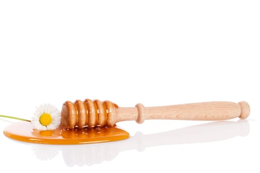 Honey spoon and daisies in honey against white background