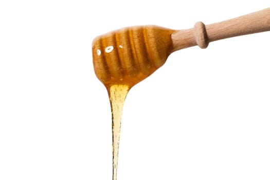 Honey flowing from a honey spoon against a white background