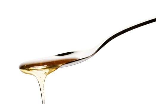 Honey flowing from a spoon against a white background