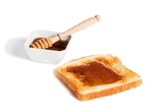 Toast with honey and a bowl of honey with a honey spoon against a white background