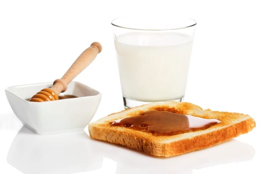 Honey on a toast with milk and a honey spoon in a bowl with honey against a white background