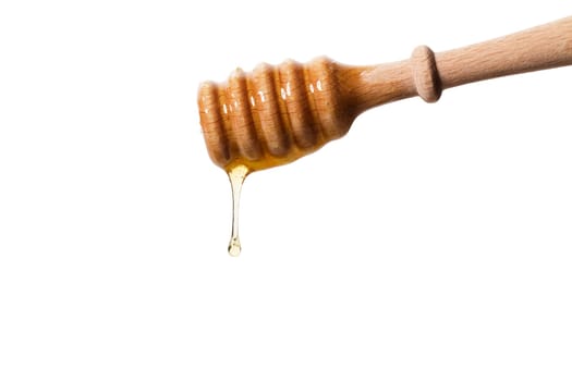 Honey dripping from a honey spoon against a white background