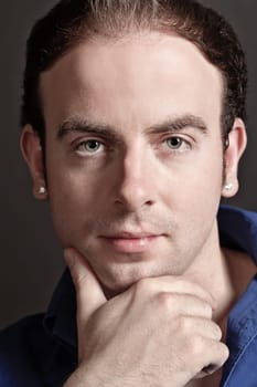 Portrait of a pensive young handsome man touching his chin