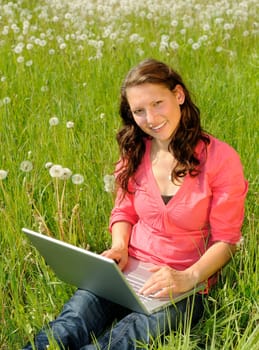 Young woman with laptop in a meadow