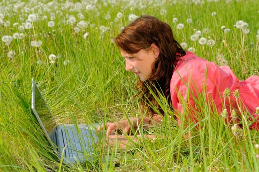 Young woman with laptop in a meadow