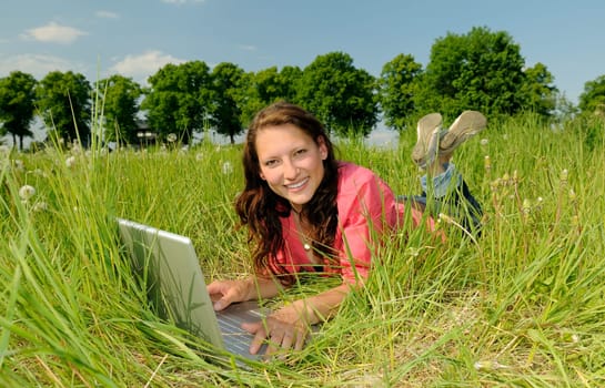 Young woman with laptop in a meadow