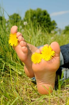 Young woman lying barefoot on a meadow