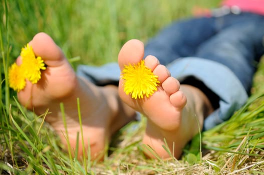 Young woman lying barefoot on a meadow