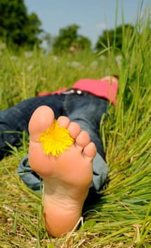 Young woman lying barefoot on a meadow