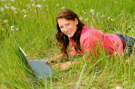 Young woman with laptop in a meadow