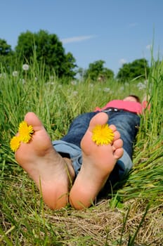 Young woman lying barefoot on a meadow