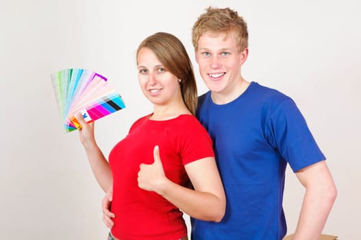 A young attractive couple renovate the stress and the first joint home. They holding a color chart and are looking out for the new wall colour.