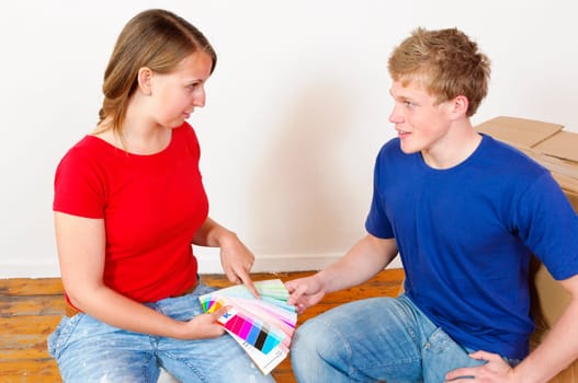 A young attractive couple renovate the stress and the first joint home. They holding a color chart and are looking out for the new wall colour.