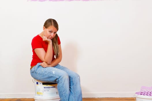 Young attractive woman with blond hair sweeps to the walls of their new home.