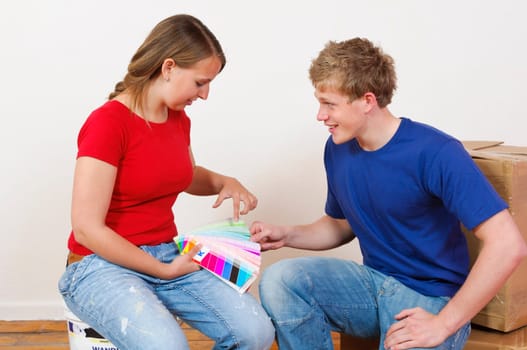A young attractive couple renovate the stress and the first joint home. They holding a color chart and are looking out for the new wall colour.