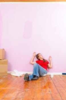 Young woman in a colorful T-shirt paints her first apartment with a paint roller.