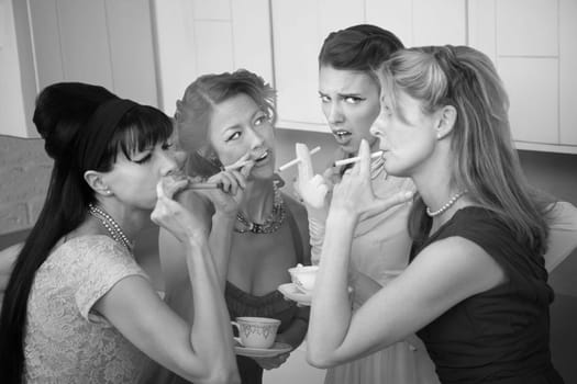 Group of four retro fashion housewives tell secrets in the kitchen