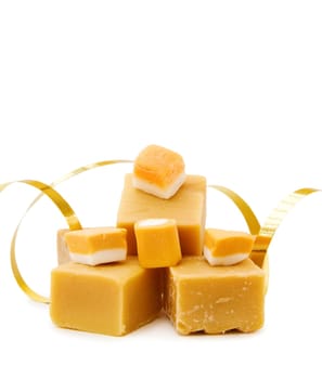 Sweets Celebration - caramel fudge and golden ribbon. Isolated on white.