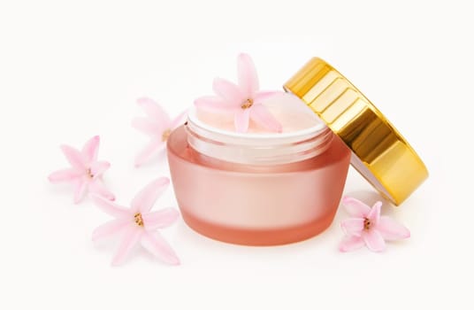 Luxury moisturizing face lotion with natural ingredients and fresh pink flowers. Isolated over white background.