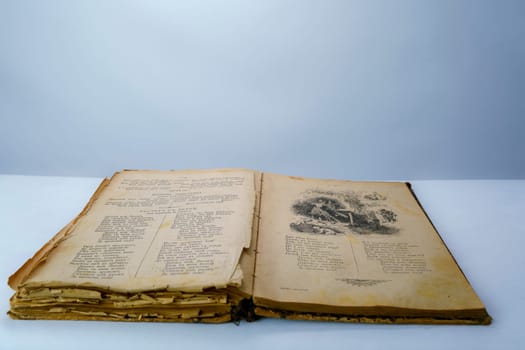 Open old book with fragile, yellowed pages and a vintage black-and-white illustration. Aged historical literature, perfect for themes of knowledge, history, and nostalgia