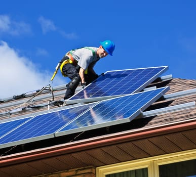 Man installing alternative energy photovoltaic solar panels on roof