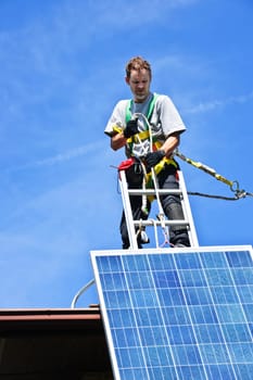 Man installing alternative energy photovoltaic solar panels on roof