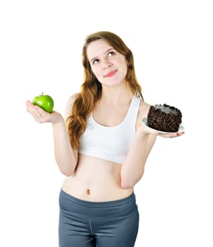 Tempted young woman holding apple and chocolate cake making a choice