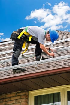 Man installing rails for solar panels on residential house roof