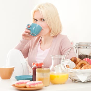 Young and blonde woman sitting at a breakfast table