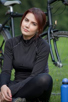 fitness woman with bike sitting on the ground having a break