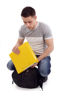 Young student packing his yellow notebook