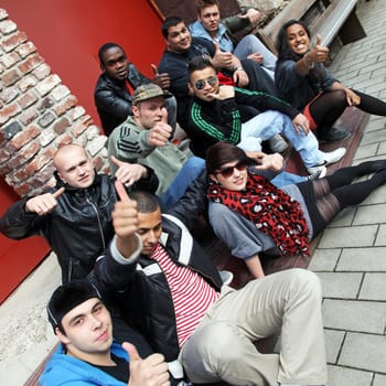 Ten young people sit together and give the thumbs up.  The group consists of boys and girls.