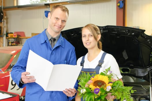 The master craftsman congratulates his apprentices on passing the exam in the car workshop.