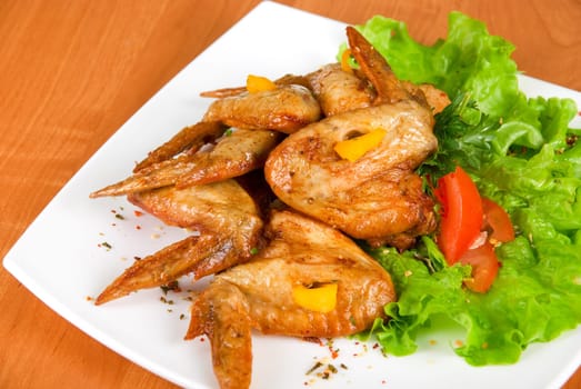 roasted chicken wings garnished with fresh green salad, pepper and greens