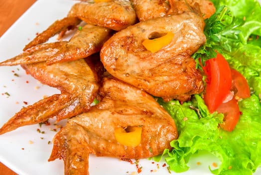 roasted chicken wings garnished with fresh green salad, pepper and greens