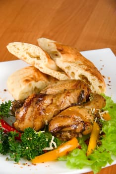 roasted chicken drumstick garnished with fresh green salad, pepper and greens