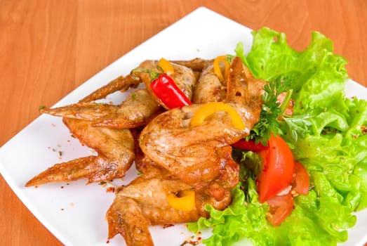 roasted chicken wings garnished with fresh green salad, pepper and greens