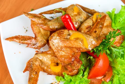 roasted chicken wings garnished with fresh green salad, pepper and greens
