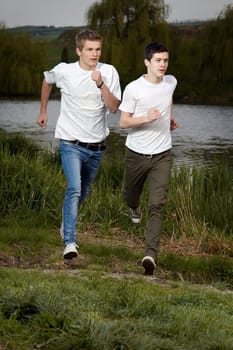Fit men jogging outdoors beside the lake park
