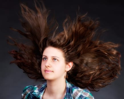 young brunette woman with long flying hair, studio shot