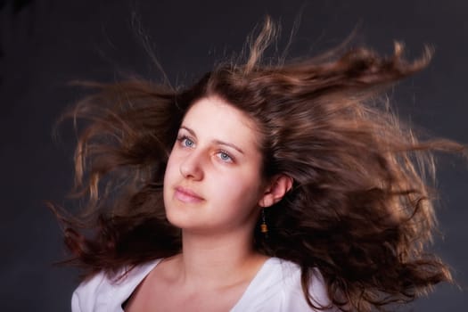 young brunette woman with long flying hair, studio shot