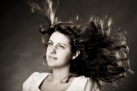 young brunette woman with long flying hair, studio shot