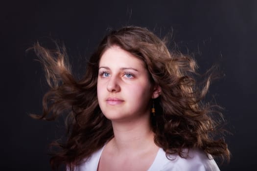 young brunette woman with long flying hair, studio shot