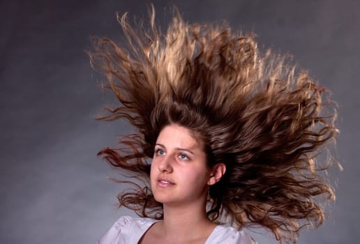 young brunette woman with long flying hair, studio shot