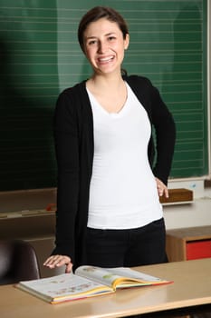 Young teacher or student with textbook. She stands at a desk and laughs