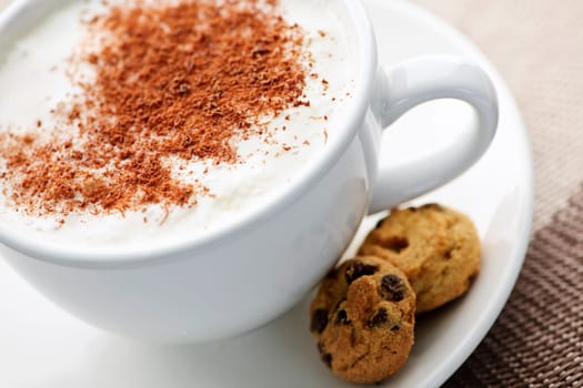 Cappuccino or latte coffee in cup with frothed milk and cookies