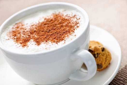Cappuccino or latte coffee in cup with frothed milk and cookies