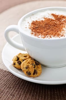 Cappuccino or latte coffee in cup with frothed milk and cookies