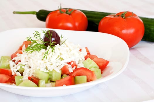 Fresh Mediterranean salad with tomatoes, cucumber, onion, feta cheese and olive on top.